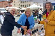 3 Personen stehen an einem Marktstand 